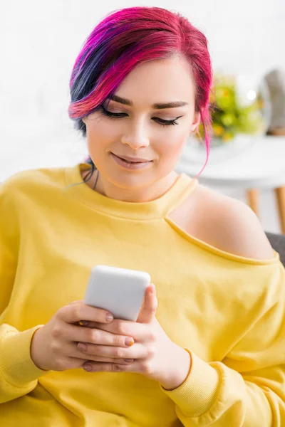 Beautiful girl in casual yellow clothes looking at smartphone — Stock Photo