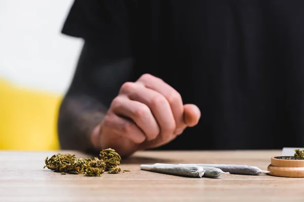 Foyer sélectif de mauvaises herbes, joints et broyeur d'herbes près de l'homme assis à table — Photo de stock