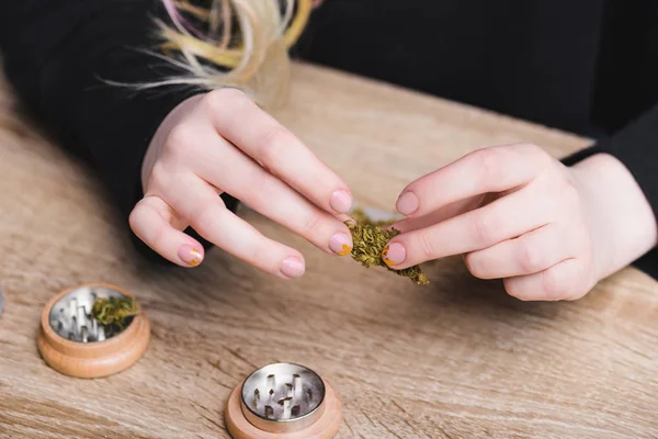 Cropped view of girl at table holding medical marijuana — Stock Photo
