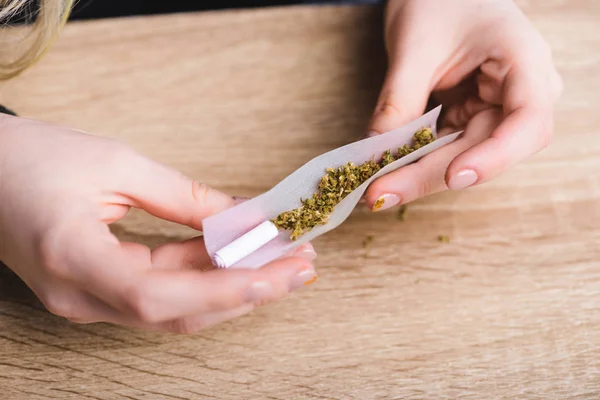 Ausgeschnittener Blick auf Mädchen, das Joint mit medizinischem Cannabis rollt — Stockfoto