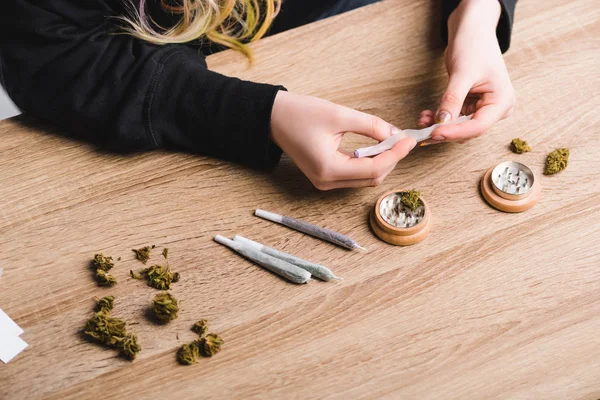 Partial view of girl rolling joint from medical marijuana — Stock Photo