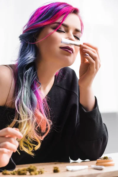 Low angle view of beautiful hipster girl sniffing joint with medical marijuana — Stock Photo