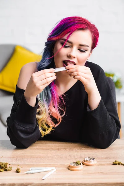 Beautiful girl with colorful hair licking joint with medical marijuana — Stock Photo