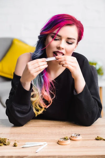 Hermosa chica con colorido pelo lamiendo conjunto con marihuana medicinal - foto de stock