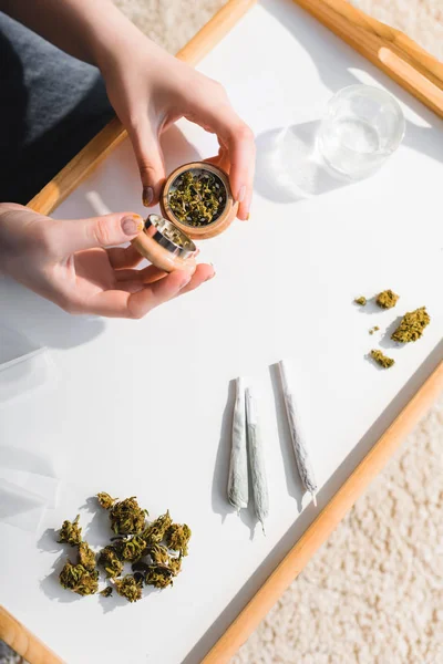 Ansicht von oben: Mädchen schließt Kräutermühle mit medizinischem Cannabis im Sonnenlicht — Stockfoto