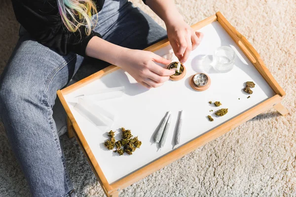 Vue recadrée de la fille mettant du cannabis médical dans une broyeuse d'herbes — Photo de stock