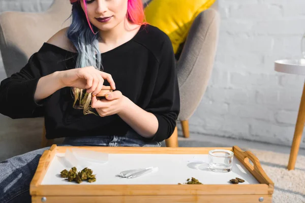 Mädchen schließt Kräutermühle mit medizinischem Cannabis auf dem Boden im Wohnzimmer — Stockfoto