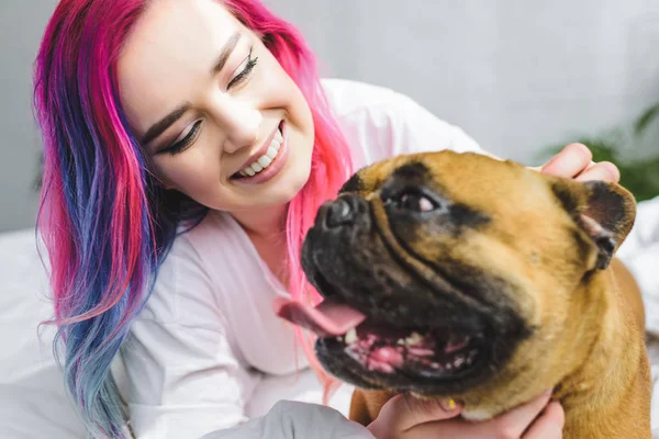 Messa a fuoco selettiva di ragazza felice con capelli colorati posa con bulldog francese a letto — Foto stock