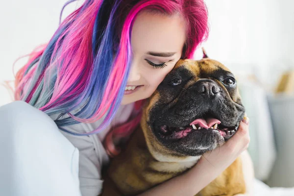 Menina alegre com cabelo colorido abraçando bulldog bonito — Fotografia de Stock
