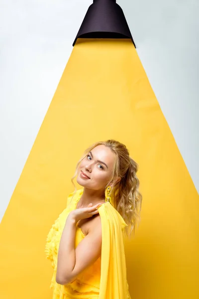 Atraente jovem mulher olhando para a câmera e posando em branco e amarelo — Fotografia de Stock