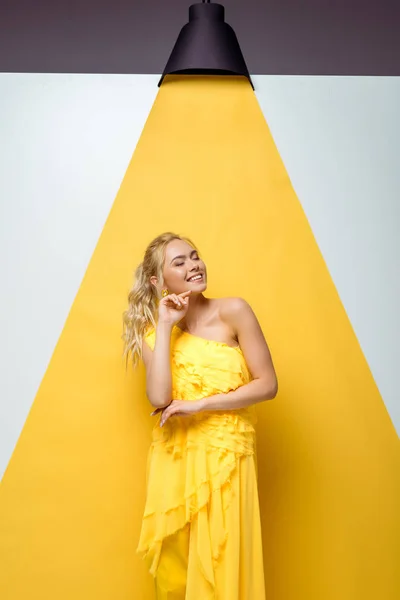 Счастливая молодая женщина с закрытыми глазами, улыбающаяся на белом и желтом — стоковое фото