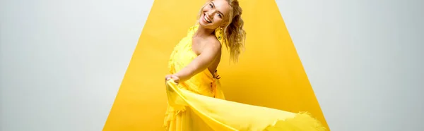 Plan panoramique de jeune femme heureuse regardant la caméra sur blanc et jaune — Photo de stock