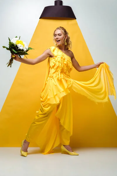 Giovane donna bionda che tiene bouquet di fiori su bianco e giallo — Foto stock