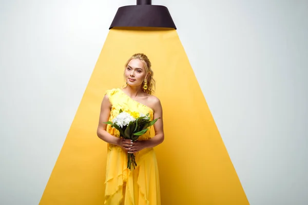 Schöne junge Frau mit Blumenstrauß auf weiß und gelb — Stockfoto
