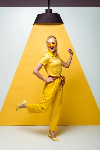 Mujer rubia feliz en gafas de sol posando en blanco y amarillo - foto de stock