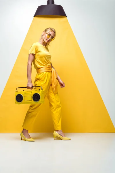 Attraktive blonde Frau posiert mit Retro-Boombox auf weiß und gelb — Stockfoto