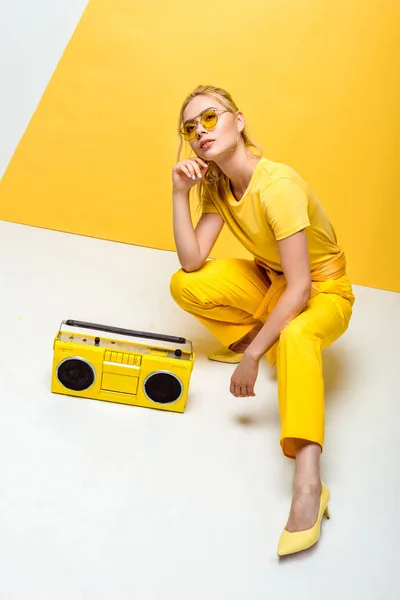 Donna elegante seduta vicino boombox retrò su bianco e giallo — Foto stock