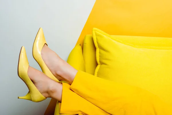 Vista recortada de la mujer en tacones cerca de almohadas en blanco y amarillo - foto de stock