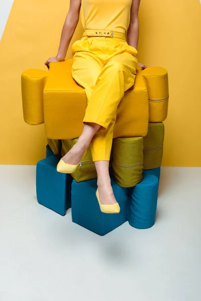 Cropped view of woman sitting on big soft puzzle pieces on white and yellow — Stock Photo