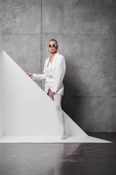 Elegante donna in occhiali da sole in posa su bianco e grigio — Foto stock