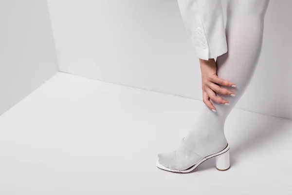 Vue recadrée de la femme élégante posant et touchant jambe sur blanc — Photo de stock