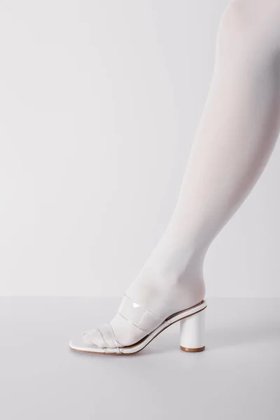 Recortado vista de la mujer joven de moda posando en zapato en blanco — Stock Photo