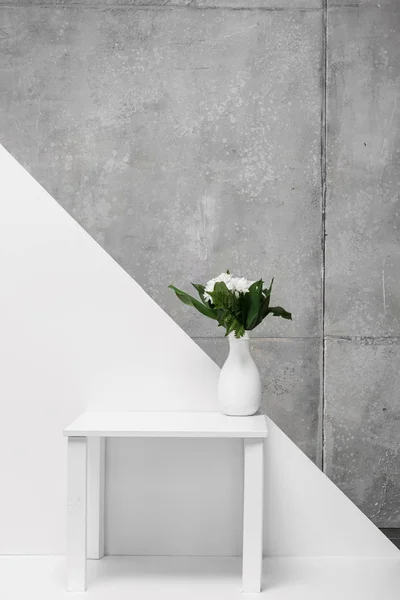 Букет цветов в вазе на столе на белом и сером — стоковое фото
