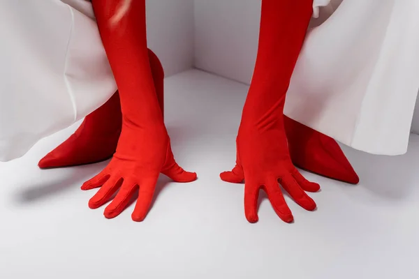 Vue recadrée de femme élégante posant dans des gants rouges et des chaussures sur blanc — Photo de stock