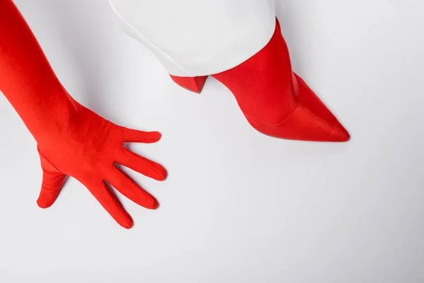 Vue recadrée de la femme élégante en gant rouge et chaussure sur blanc — Photo de stock