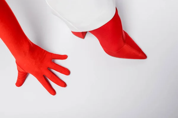 Vista recortada de la mujer con estilo en guante rojo y zapato en blanco - foto de stock