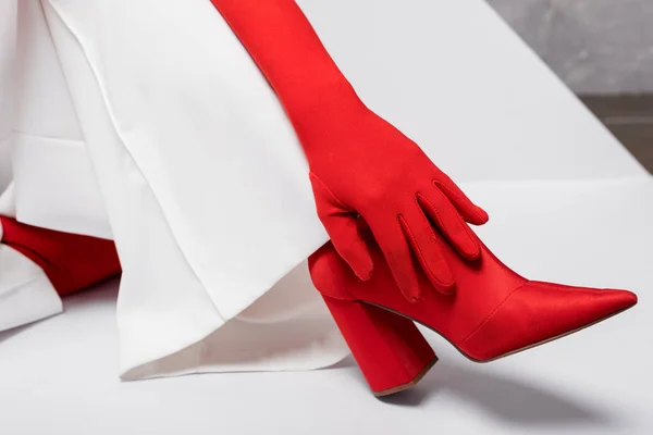 Vue recadrée de la jeune femme élégante en gant rouge et chaussure sur blanc — Photo de stock