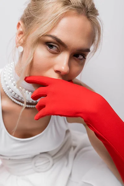 Selective focus of blonde woman in red glove covering face on white — Stock Photo
