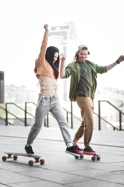 Glückliches Paar in Freizeitkleidung Händchen haltend auf Skateboards in der Stadt — Stockfoto