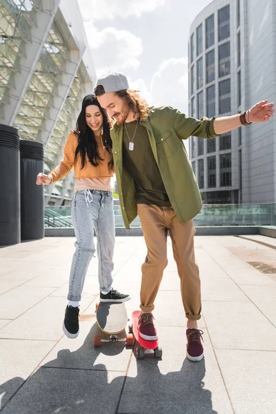 Donna allegra e uomo a cavallo su skateboard — Foto stock