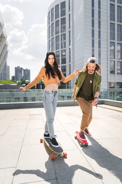 Mulher e homem montando em skates no telhado — Fotografia de Stock