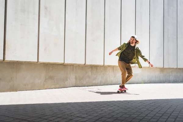 Взрослый мужчина катается на скейтборде возле бетонной стены — стоковое фото