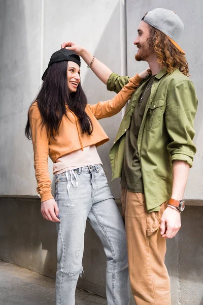 Glückliches Paar in Freizeitkleidung, das sich anschaut und nahe der Wand steht — Stockfoto