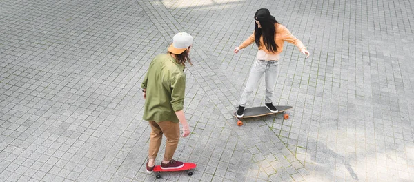 High angle view of young woman with man riding on skateboards on street — Stock Photo