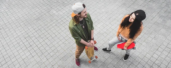 High angle view of happy man and woman skaters looking at each other, standing on street — Stock Photo