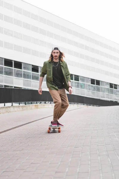 Bel homme en tenue décontractée chevauchant sur skateboard à la rue — Photo de stock