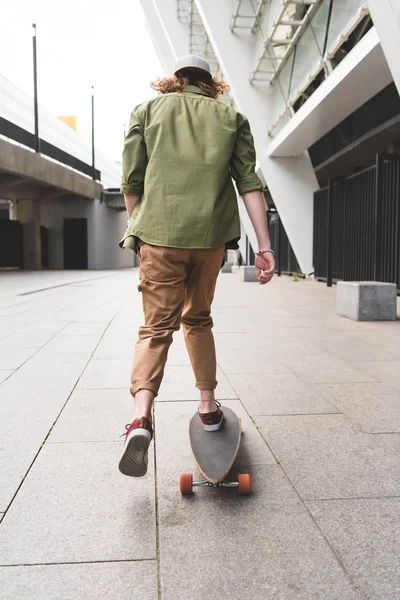 Back view of man in casual wear riding on skateboard — Stock Photo