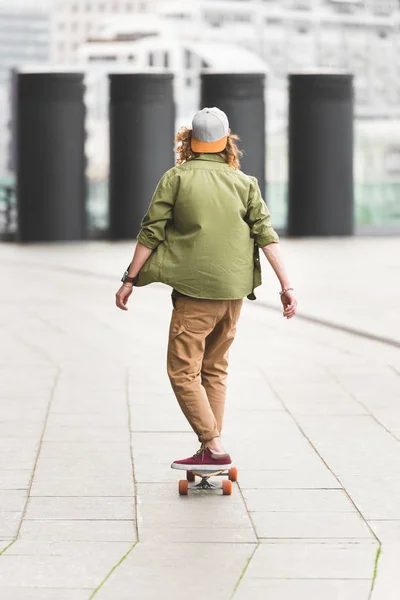 Visão traseira do homem montando no skate no telhado — Fotografia de Stock