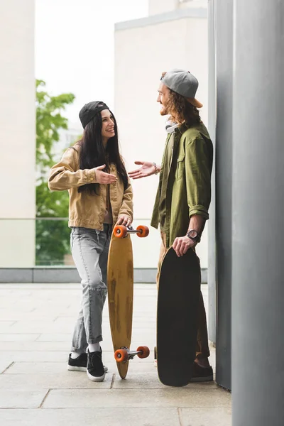 Vista laterale di bell'uomo in piedi vicino skateboard sul tetto, stringendo la mano con la ragazza — Foto stock