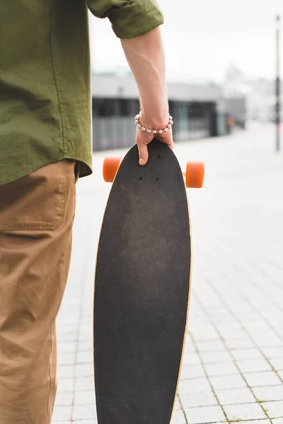 Vista ritagliata dell'uomo in abbigliamento casual in piedi con lo skateboard in mano — Foto stock