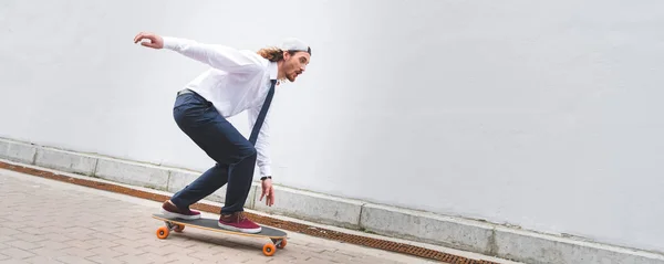 Vista panoramica di bellissimo uomo d'affari che cavalca sullo skateboard in strada — Foto stock