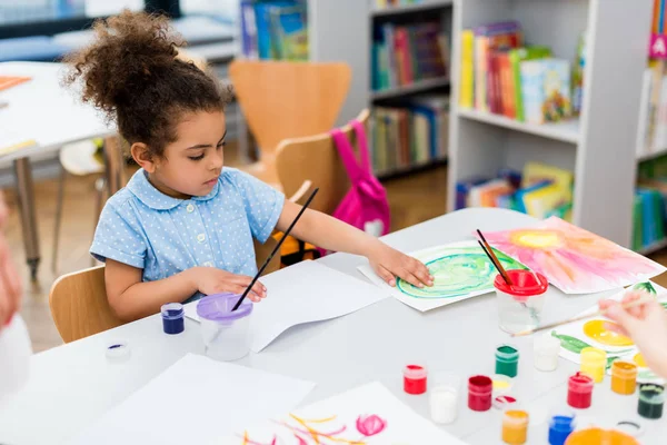 Selective focus of african american kid touching paper with drawing — Stock Photo