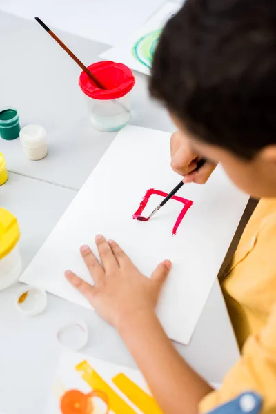 Overhead view of african american kid painting with red gouache paint on paper — Stock Photo