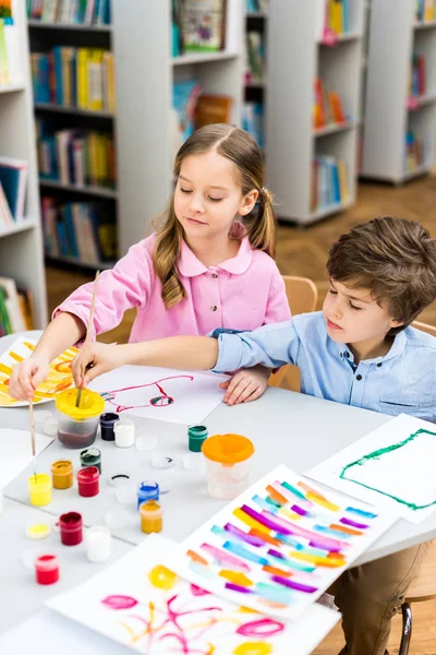 Selective focus of cheerful kids holding paintbrushes near papers — Stock Photo