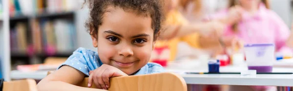 Plan panoramique de heureux afro-américain enfant souriant et regardant la caméra — Photo de stock