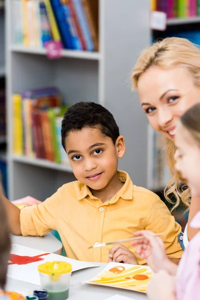 Selective focus of happy african american kid looking at camera near smiling woman and child — Stock Photo